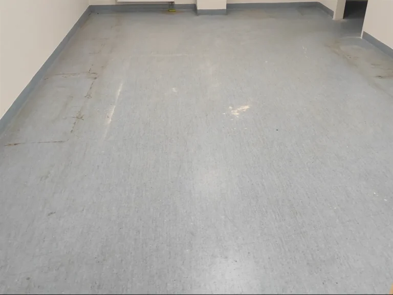 Zniszczona wykładzina biurowa PCV przed czyszczeniem i renowacją.