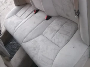 Tekstylna kanapa tapicerowana w samochodzie przed praniem. Widoczne plamy.